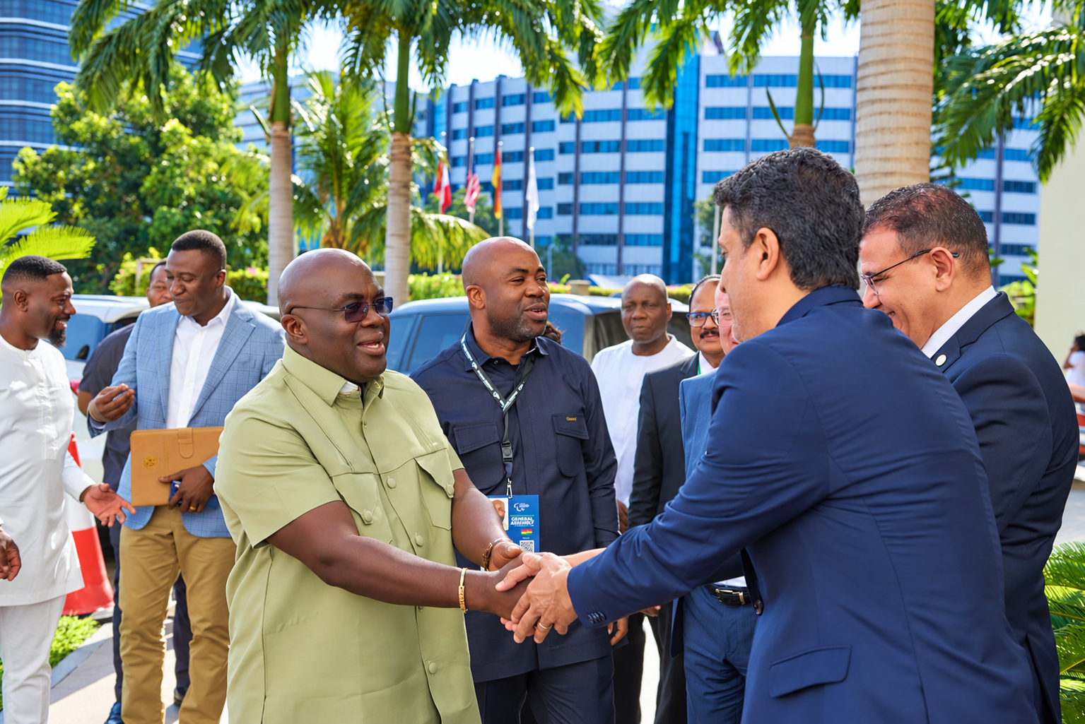 Guests greet one another outdoors beside palm trees and the event venue.