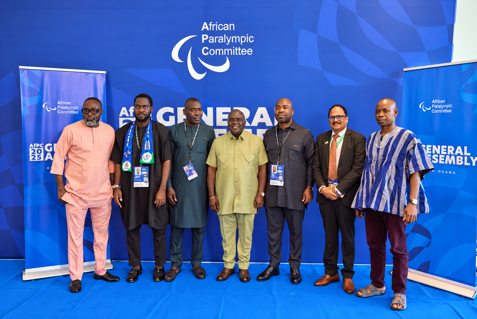 Seven participants standing together in front of the AfPC General Assembly backdrop in Accra.