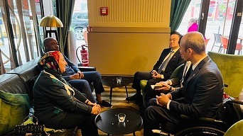 Miembros de las delegaciones africana y coreana celebran una reunión sentados.