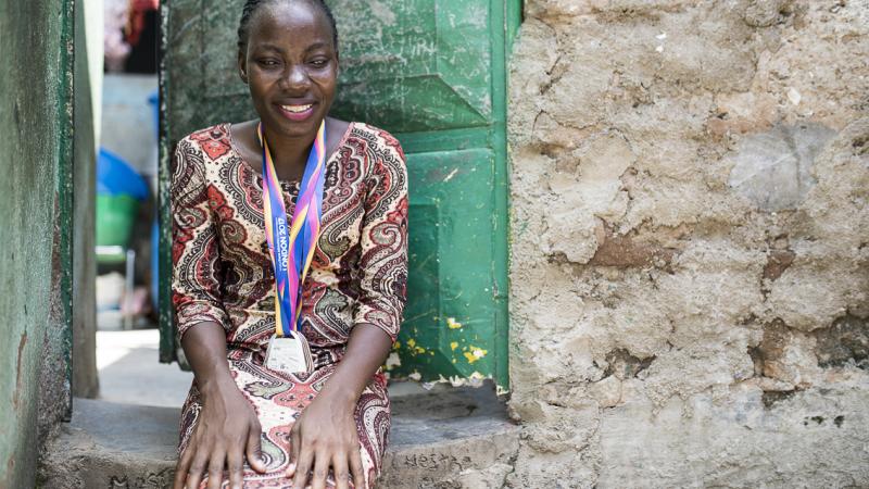 Esperança Gicasso holds two medals outside her home.