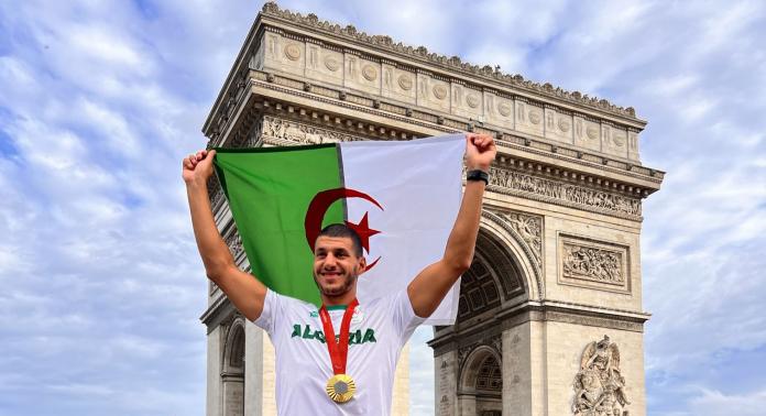 Guendouz holds an Algerian flag near the Arc de Triomphe.