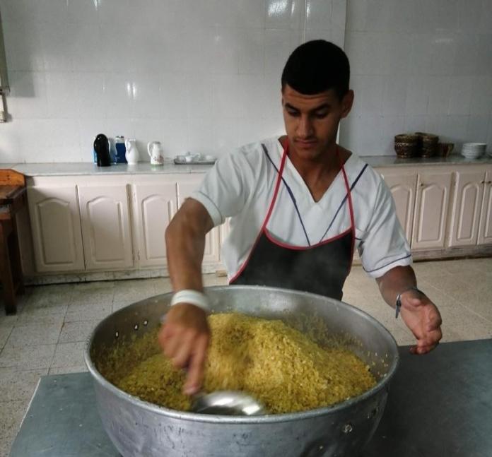 Guendouz cooking a meal.