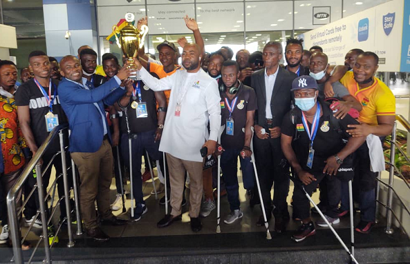 Ghana’s amputee football team and supporters gather with a trophy.