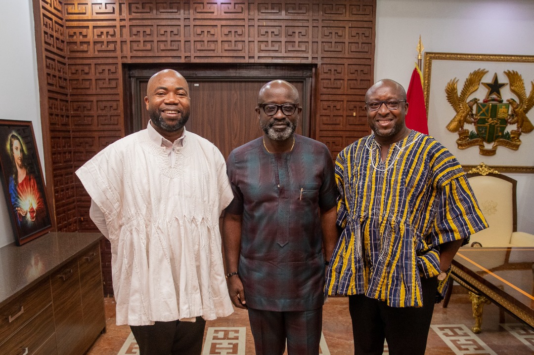 Three delegation members pose against carved wooden panels in the archive collection.